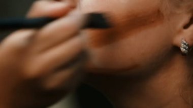 Makyöz, genç bir kadının profesyonel makyajını yapıyor..