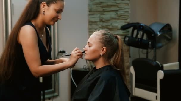 Maquillar artista haciendo profesional maquillaje de mujer joven — Vídeo de stock