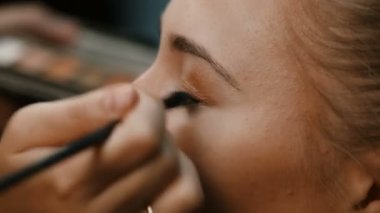 Makyöz, genç bir kadının profesyonel makyajını yapıyor.