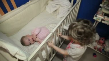 Kız bebek kız kardeşleri ile yatağın duruyor.