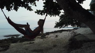 Sahildeki hamakta telefonlu bir kadın..