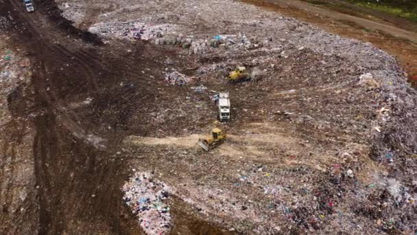 Mülldeponie. Ein riesiger Müllhaufen, umgeben von Wald. Müllwagen bringen Müll zu einer Mülldeponie. Eine Schar weißer Möwen fliegt über einen Müllberg. — Stockvideo
