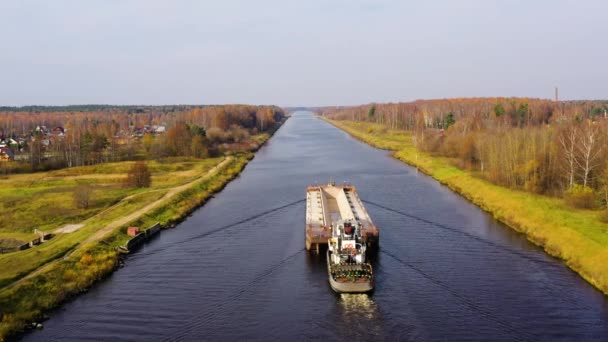 Річковий буксир переміщує вантажну баржу на річці. Осінній пейзаж . — стокове відео