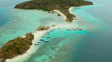 Beyaz kumlu sahili olan küçük torpik bir ada..