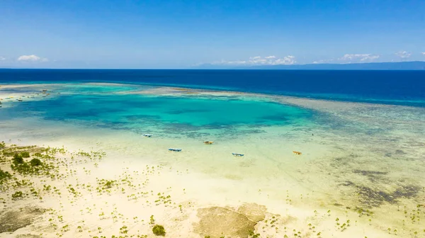 Atoll with turquoise water and boats.