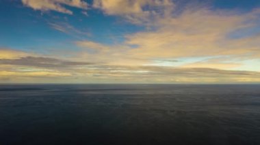 Zaman aşımı: Gün batımında denizin üzerindeki bulutlu gökyüzü.