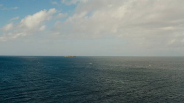 Deniz manzarası, mavi deniz, bulutlu ve adalı gökyüzü.