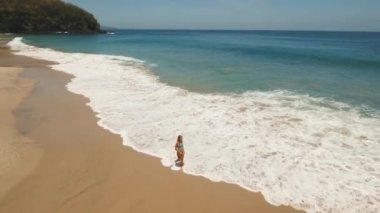 Kumsalda yürüyen bir kız. Bali, Endonezya.