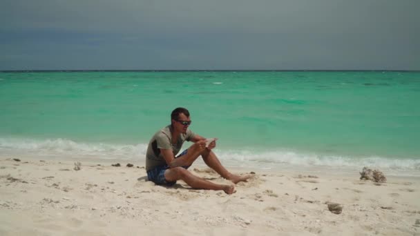 Homme avec une tablette sur une plage tropicale. — Video
