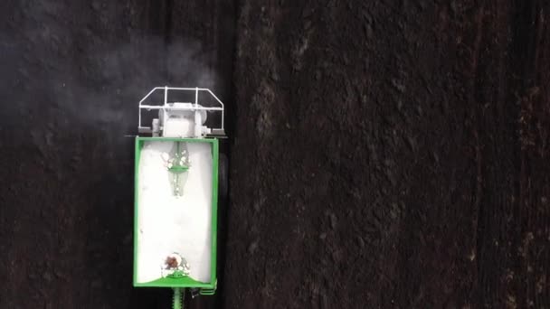 Трактор разбрасывает сухие минеральные удобрения на поле. — стоковое видео