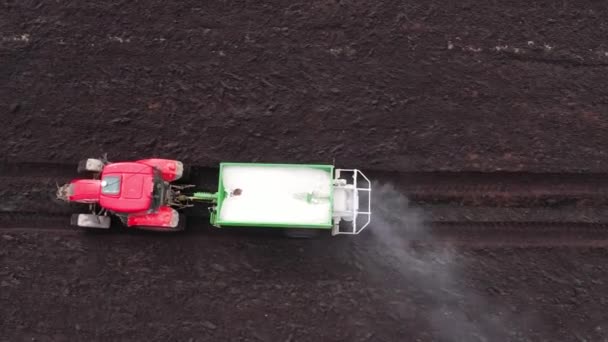 Трактор разбрасывает сухие минеральные удобрения на поле. — стоковое видео