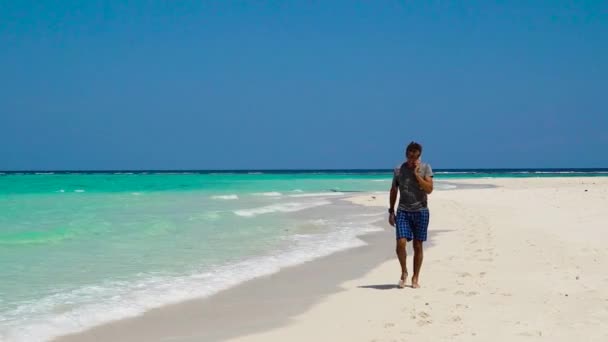 Uomo con cellulare sulla spiaggia tropicale. — Video Stock