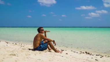 Kumsalda bira içen adam.