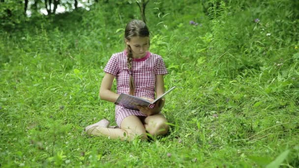 Jovencita leyendo libro en el parque — Vídeo de stock