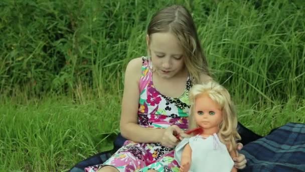 Niña jugando con la muñeca en la hierba exterior — Vídeos de Stock