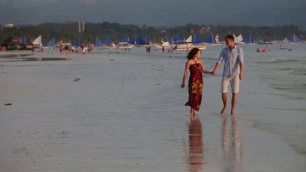 Paar lopen samen langs het strand bij zonsondergang — Stockvideo