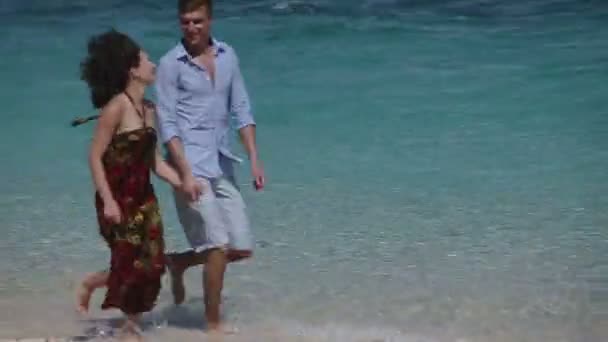 Счастливая пара бегает по тропическому пляжу — стоковое видео