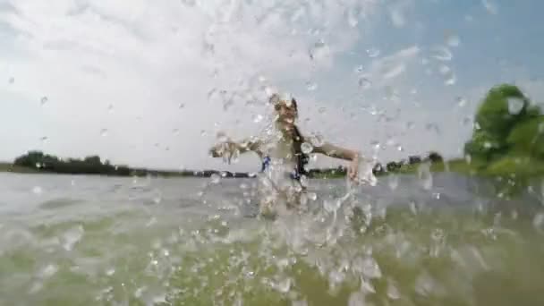 Chica joven salpicando el agua en el lago . — Vídeo de stock