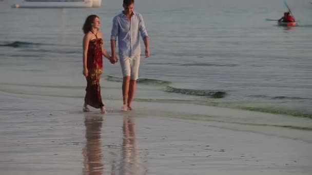 Casal caminham juntos ao longo da praia ao pôr do sol — Vídeo de Stock