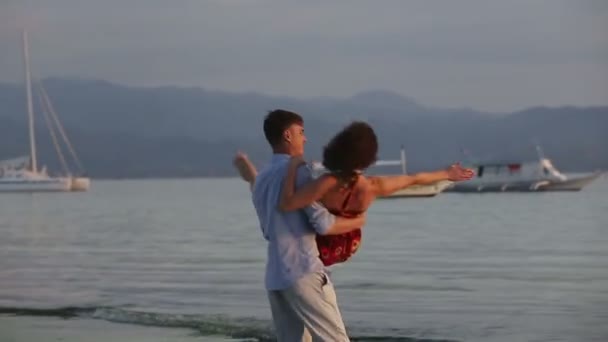 Man turns meisje op het strand bij zonsondergang — Stockvideo