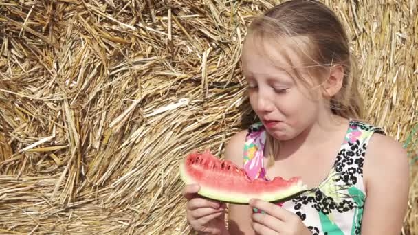 Mädchen essen Wassermelone nahe dem Heuhaufen — Stockvideo