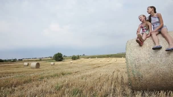 Two girl sits on haystack. — Stock Video