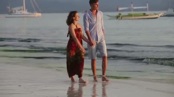 Pareja caminar juntos a lo largo de la playa al atardecer — Vídeos de Stock