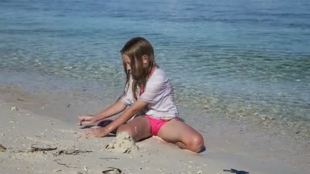 Glückliches Kind, das im Sommer am Strand mit Sand spielt. — Stockvideo