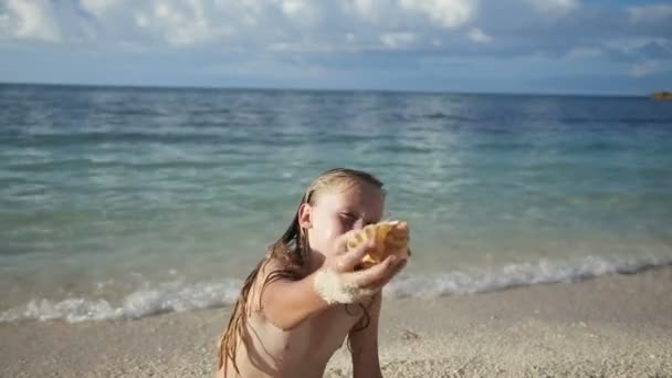 Bambino che tiene una conchiglia sulla spiaggia — Video Stock