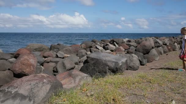 Дівчина на кам'янистому пляжі грає на каменях — стокове відео