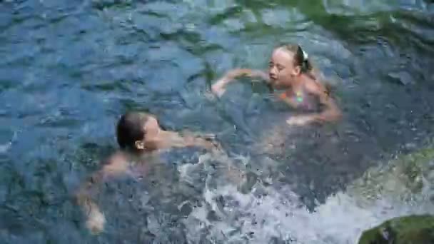 Jong meisje zwemmen in een waterval — Stockvideo
