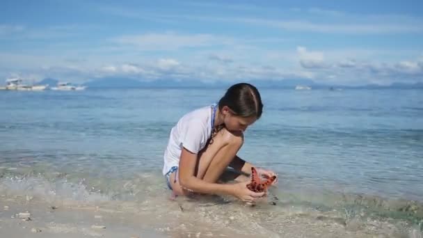 Menina brincando com uma estrela do mar — Vídeo de Stock