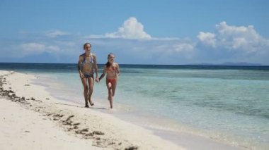 İki kız bir tropik sahilde yürümek