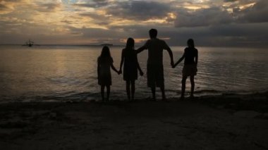 Aile silueti gün batımında sahilde
