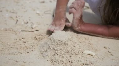 Yaz aylarında kumsalda kumla oynayan mutlu çocuk.