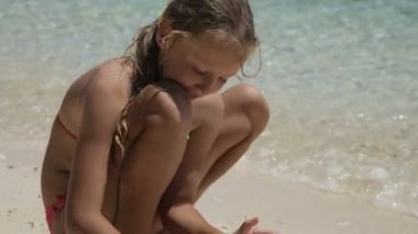 Yaz aylarında kumsalda kumla oynayan mutlu çocuk.