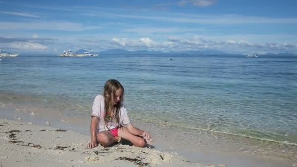 Šťastné dítě hraje s pískem na pláži v létě.