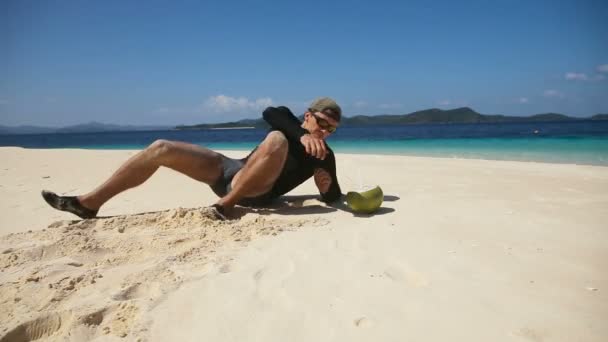 Человек на пляже пьет кокосовый сок — стоковое видео