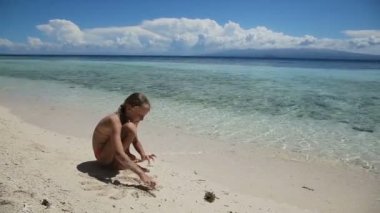 Yaz aylarında kumsalda kumla oynayan mutlu çocuk.