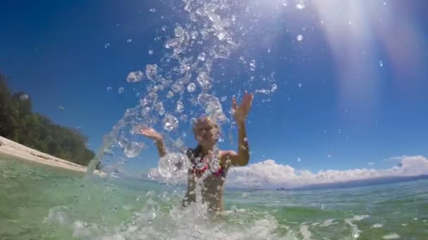 Молодая девушка плещущая воду в море — стоковое видео