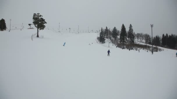 Esquiadores y snowboarders esquiando cuesta abajo — Vídeo de stock