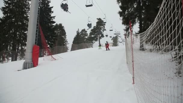 Esquiadores y snowboarders esquiando cuesta abajo — Vídeo de stock