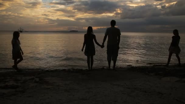 Silhouet van familie op het strand bij zonsondergang — Stockvideo