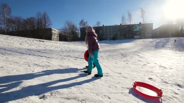 Les filles avec un traîneau vers le haut de la colline — Video