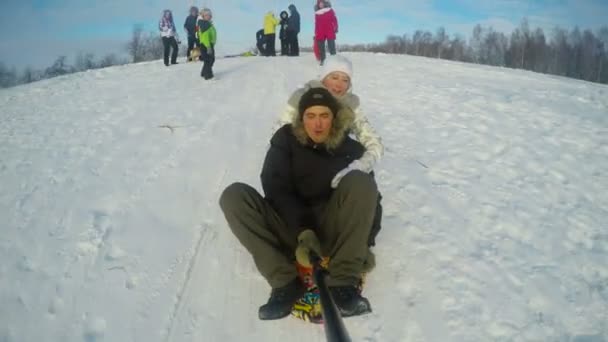 Father and daughter sledging down hill — Stock Video