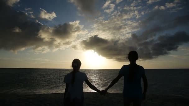 Silhuett av flickor på stranden vid solnedgången — Stockvideo