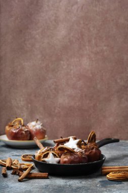 Yıldız kurabiyeleriyle süslenmiş demir tavada bulunan elmalar tarçın çubukları, kuru portakal şekeri ve tarçın tozu. Noel yemekleri konsepti.