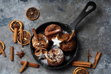 Yıldız kurabiyeleriyle süslenmiş demir tavada bulunan elmalar tarçın çubukları, kuru portakal şekeri ve tarçın tozu. Noel yemekleri konsepti.