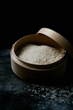 Tipik bir Japon ahşap küvetinde çiğ pirinç koyu arka planda hangiri. Seçici odak