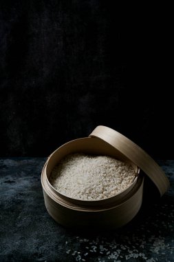 Tipik bir Japon ahşap küvetinde sade pirinç, koyu arkaplanda hangiri. Seçici odak